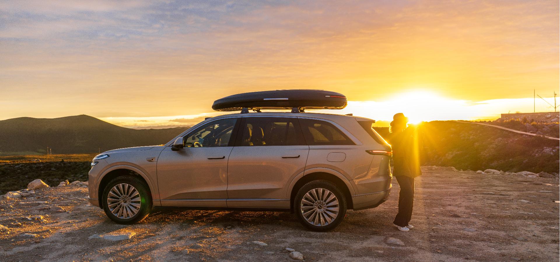 Wheelsboyselect Enroad Roof Box mounted on a silver SUV at sunset, 2025 Red Dot award-winning aerodynamic cargo carrier for smart travel.
